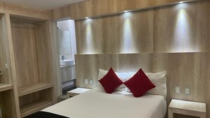 Une chambre d’hôtel moderne avec un grand lit, une tête de lit en bois et des tables de chevet.