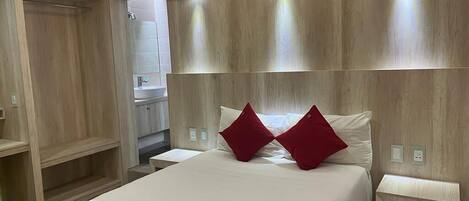 A modern hotel room with a large bed, wooden headboard, and bedside tables.