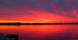Un atardecer sobre un lago tranquilo con un puente a lo lejos.