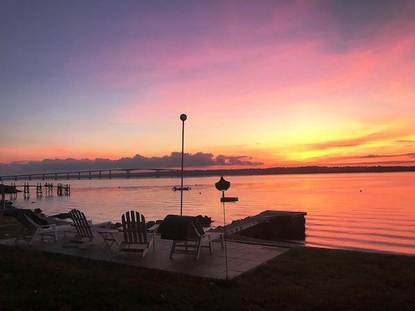 Vista del atardecer desde un muelle con sillas de descanso al borde del lago.