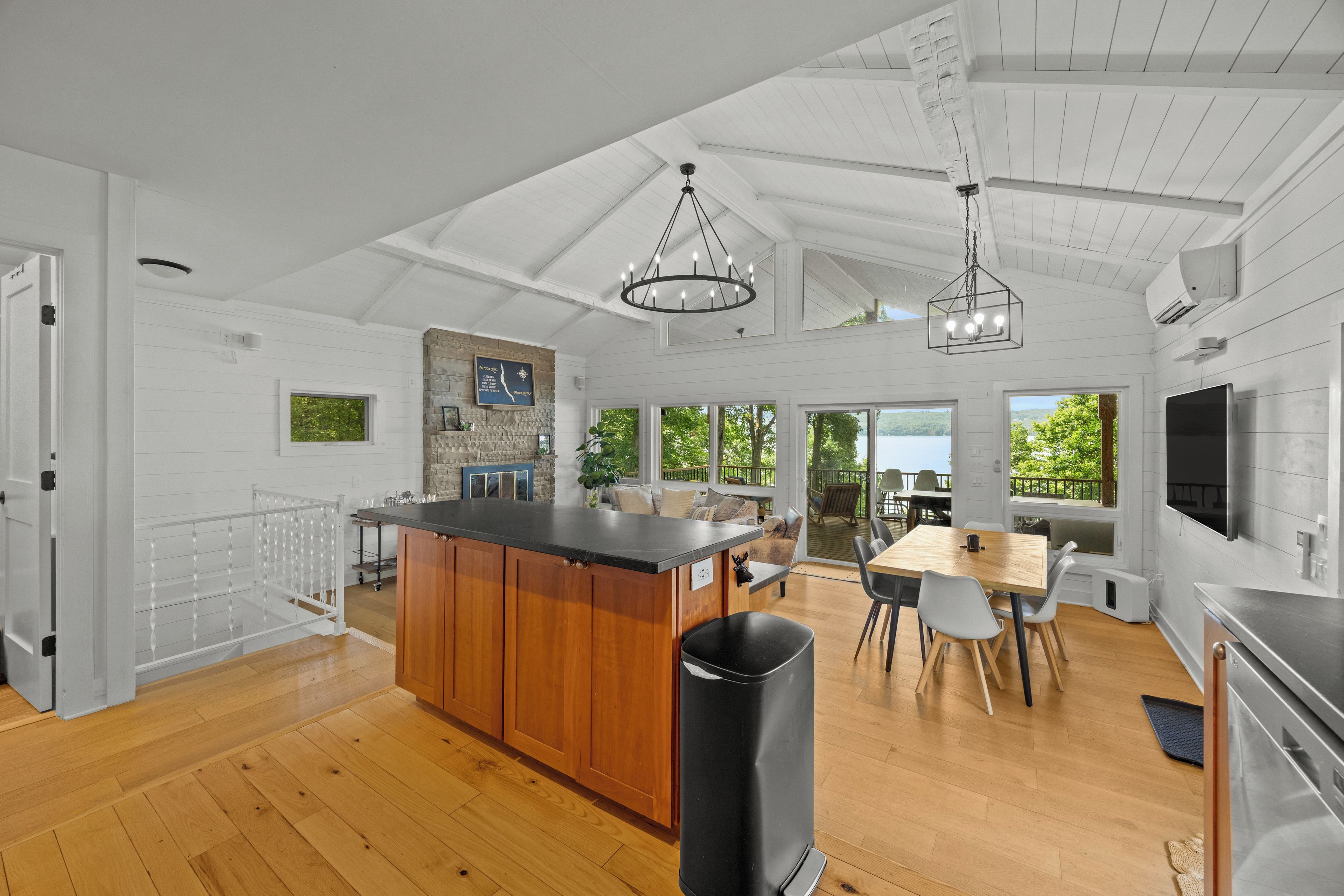 Una cocina amplia con una isla de madera, un comedor con mesa y sillas, y vistas al exterior a través de ventanas grandes.