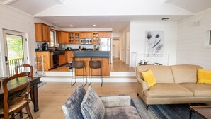 A modern kitchen with wooden cabinets, a central island, and a dining area with a wooden table and chairs.