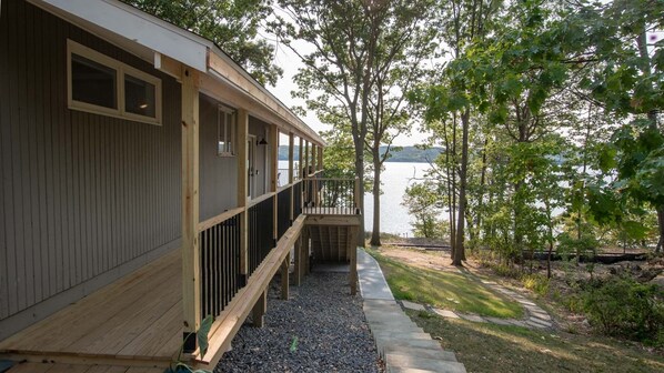 A wooden cabin with a deck overlooking a lake, surrounded by trees.