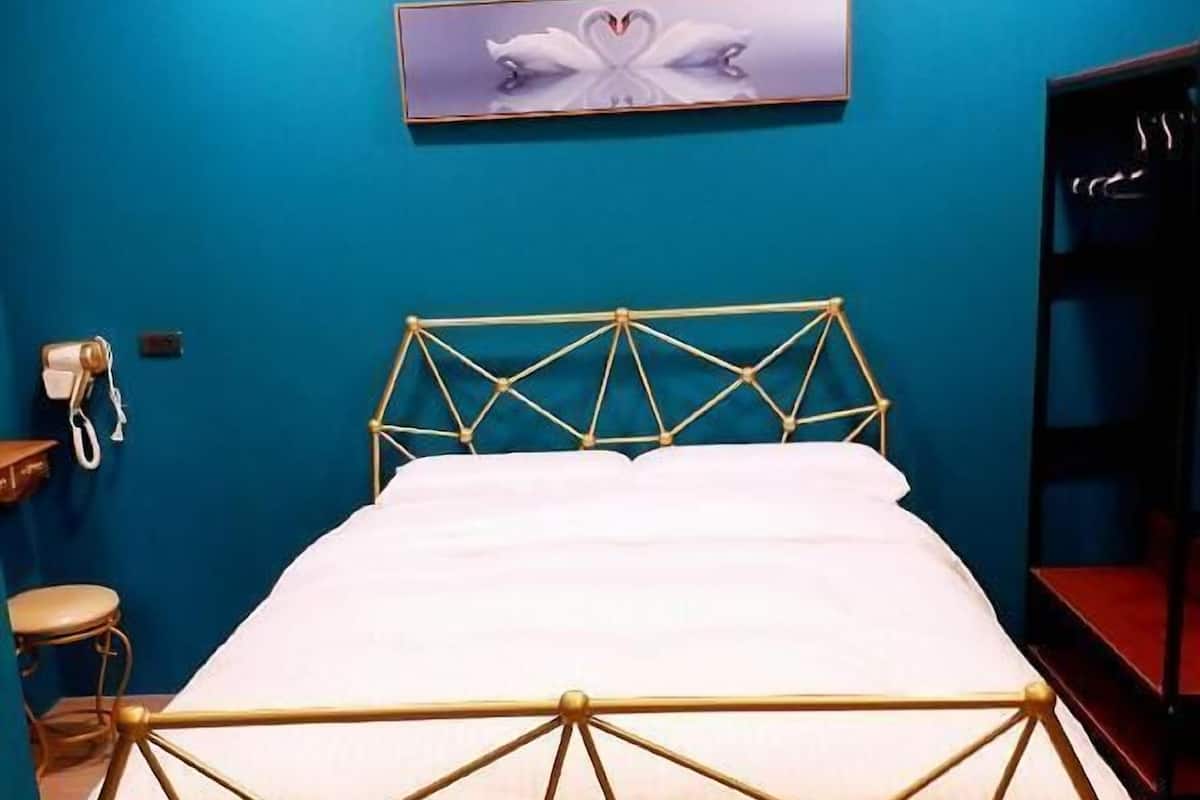 A bed with a geometric metal frame, a white mattress, and a blue wall with a heart-shaped artwork above it.