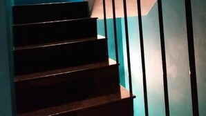 Una escalera con barandillas negras y una pared azul.