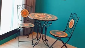 Una habitación con paredes color turquesa, una mesa redonda y dos sillas con respaldo decorativo.