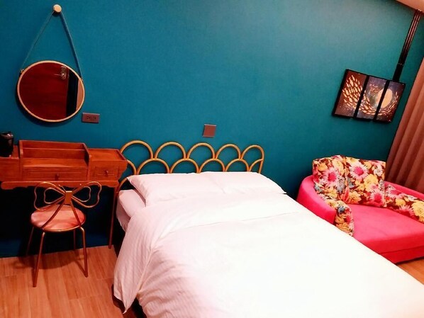 A bedroom with a bed, a desk, a chair, a mirror, and a sofa.