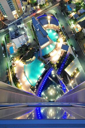 Ett högt hotell med en pool på taket, flera badområden och en glasbeklädd innergård.