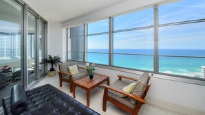 A balcony with a view of the ocean, furnished with a sofa, chairs, and a table. - Holidays Gold Coast (Surfers Paradise)