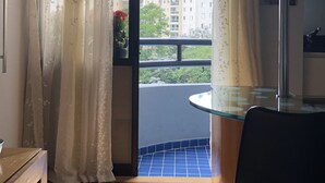 A room with a balcony, a dining table, and a chair. - Cozy and Cozy Apartment Portal do Morumbi (Vila Suzana)
