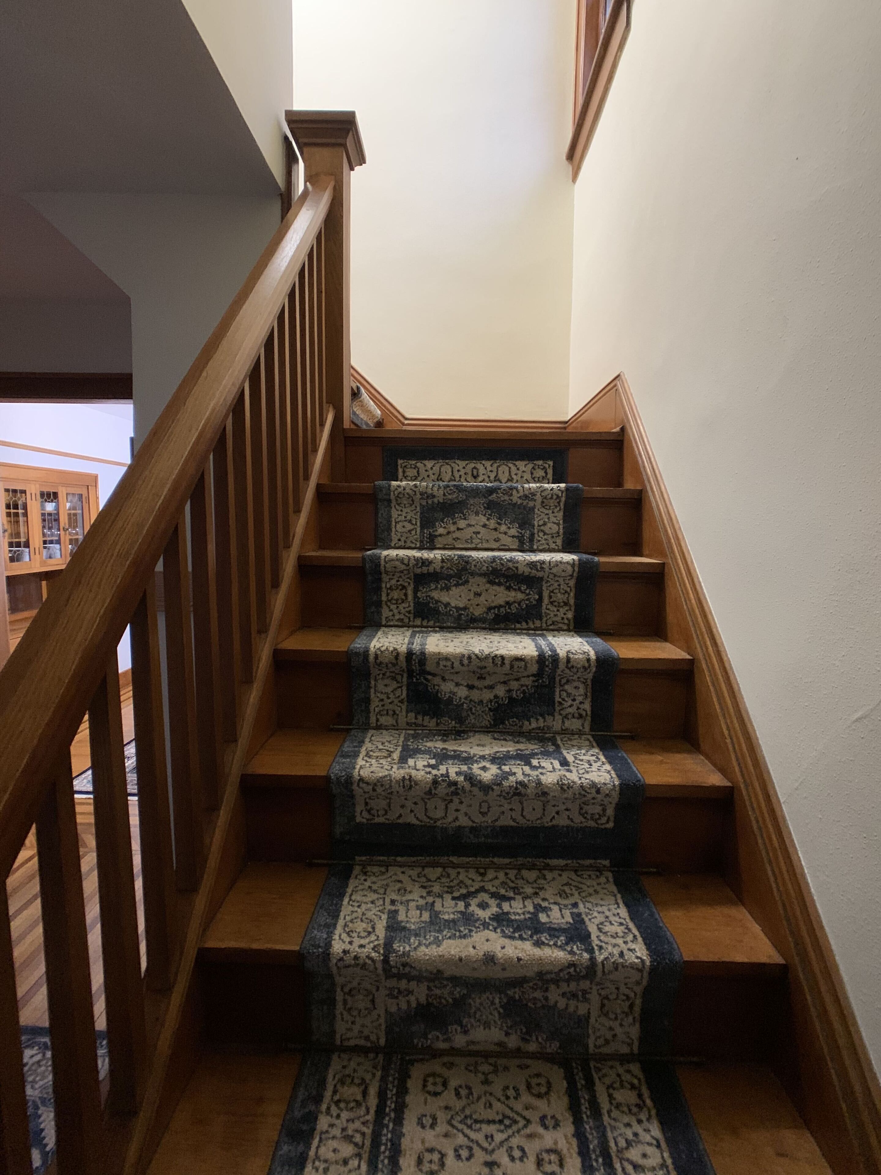 A wooden staircase with patterned carpet runners.