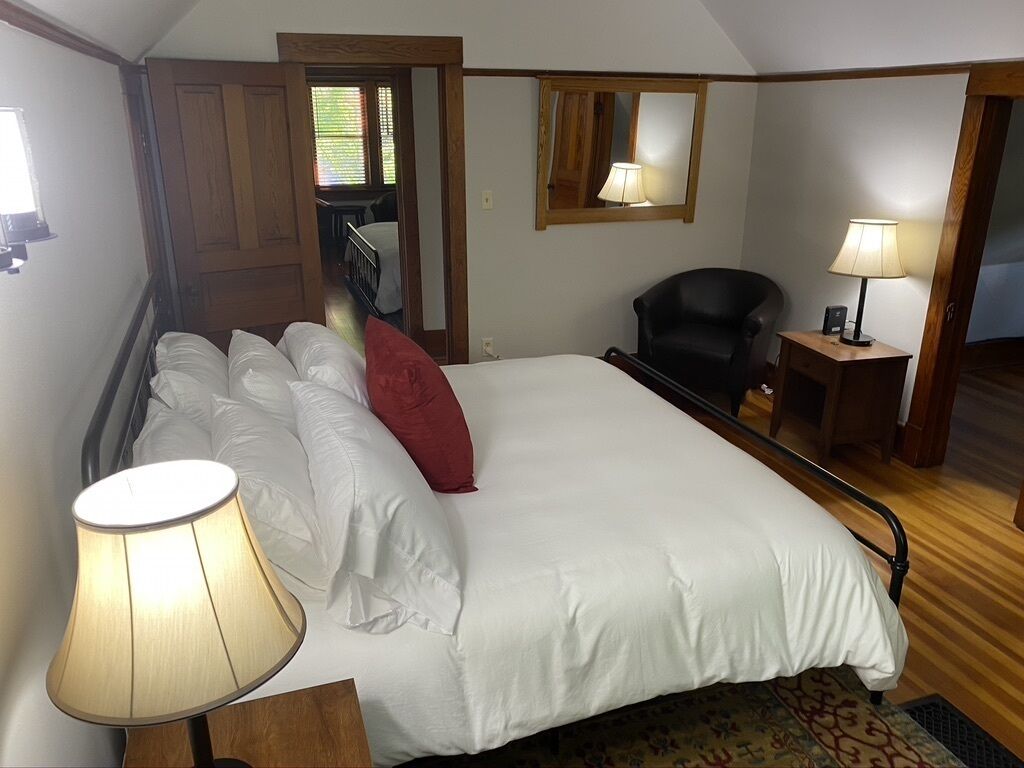 Une chambre à coucher avec un grand lit, une chaise, un bureau et un miroir.