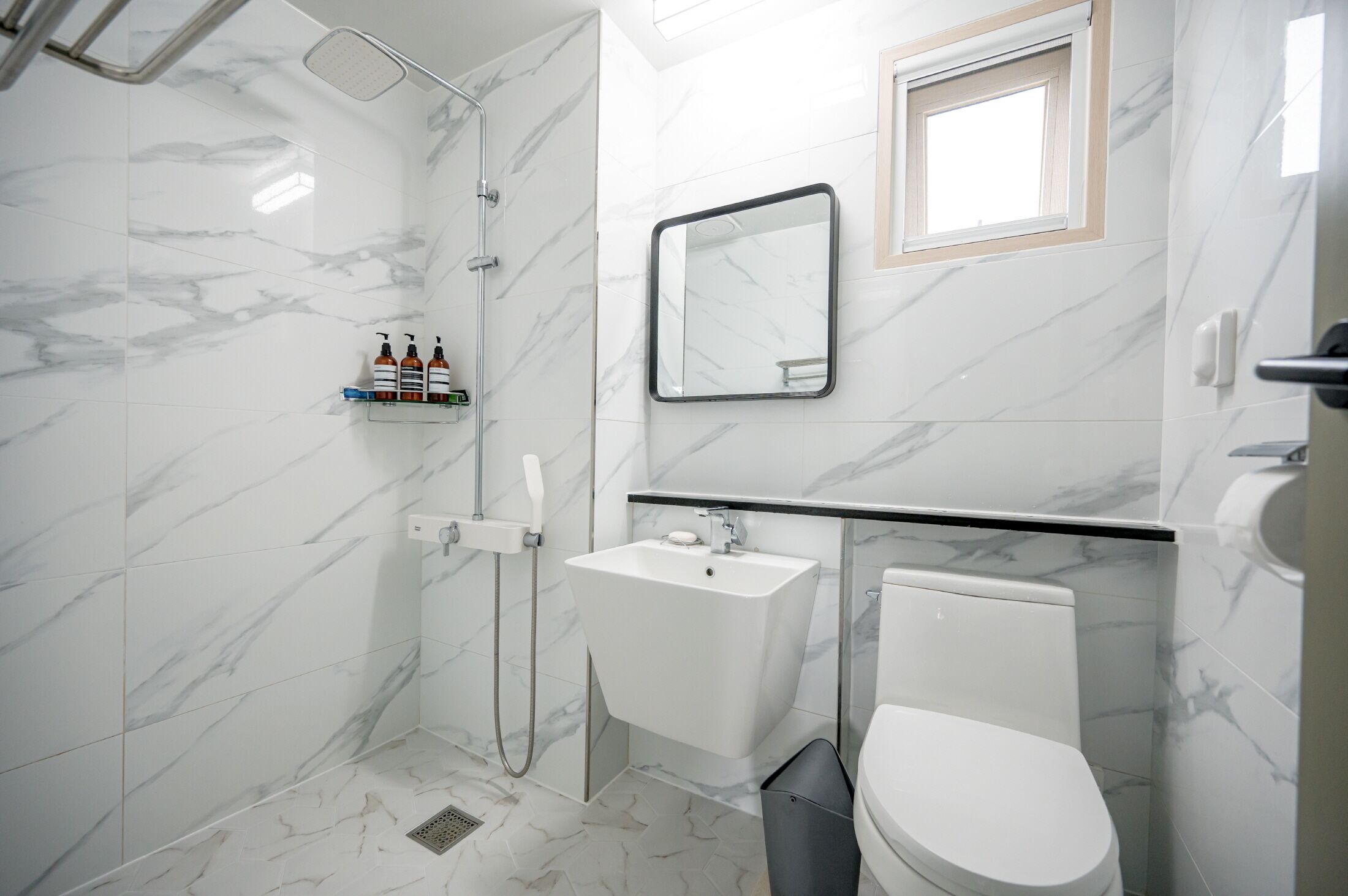 A modern bathroom with a shower, toilet, sink, and a mirror.