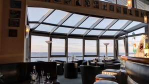 A restaurant with a glass ceiling, tables with wine glasses, and a view of the sea. - Holiday home with WIFI and terrace (Damp)