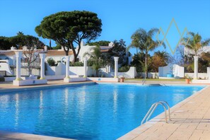 Una piscina con pilares blancos y un cielo azul despejado.