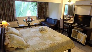 A hotel room with a bed, a desk with a computer, a TV, and a small table with a chair. - OYO 903 Madame Kim Hostel (Lampang)