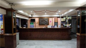 A reception area with a marble floor, a reception desk, and a wall-mounted television. - OYO 903 Madame Kim Hostel (Lampang)