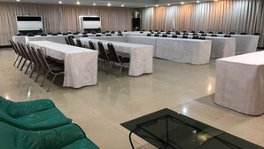 A conference room with long tables and chairs, a projector, and curtains. - OYO 903 Madame Kim Hostel (Lampang)