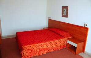 Ein Einzelbett mit Holz Kopfteil und einer rot gepunkteten Bettdecke.