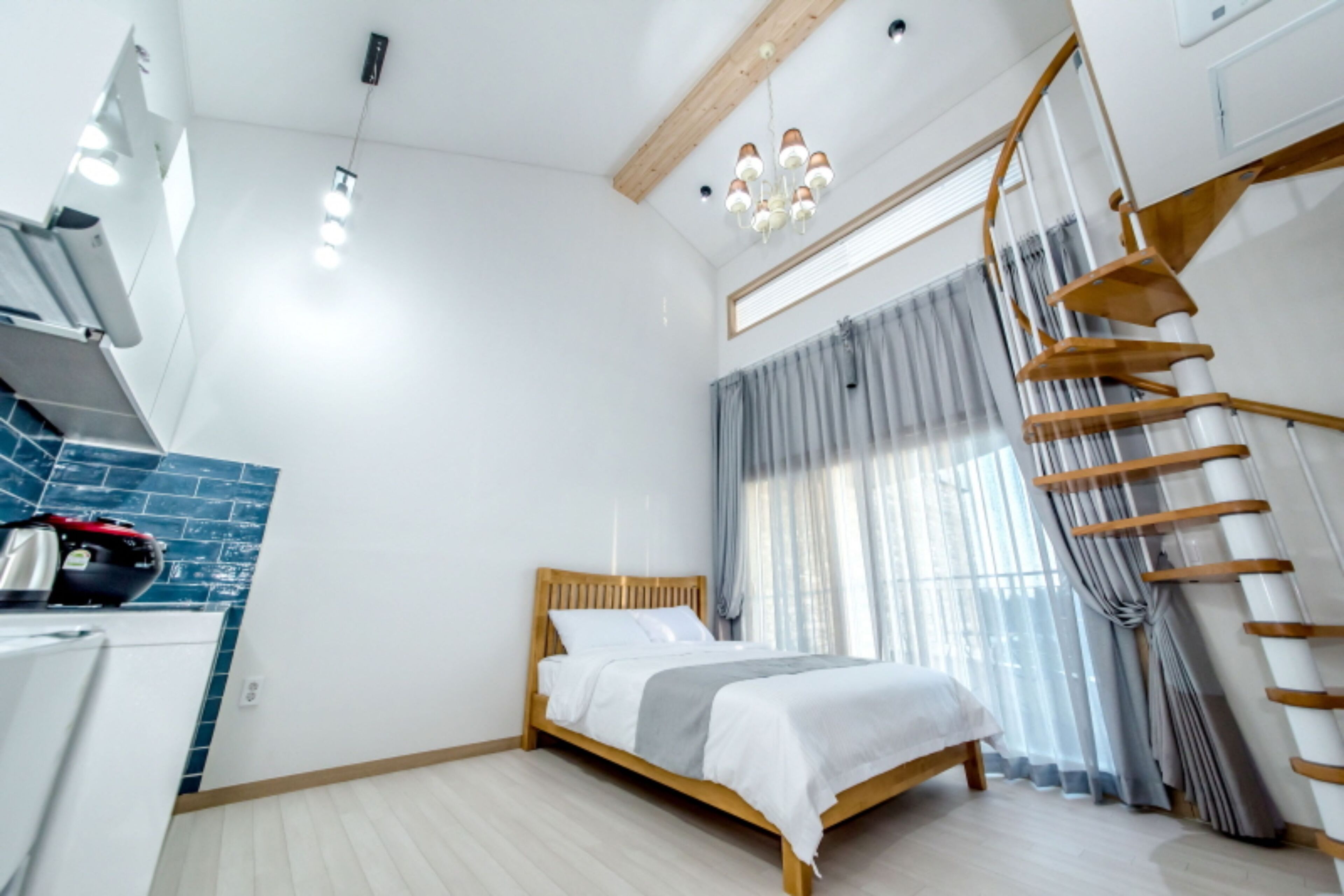 A modern bedroom with a wooden bed, a built-in desk, and a spiral staircase.