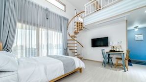 A bedroom with a wooden bed, a spiral staircase, a desk with chairs, and a TV on the wall. - Swimeong Spa Pension (Seogwipo)