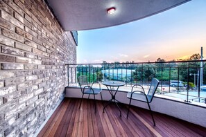A balcony with a brick wall, wooden floor, and metal chairs. - Swimeong Spa Pension (Seogwipo)