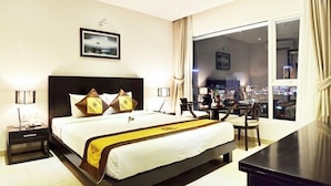 A hotel room with a large bed, a desk, and a view of the city at night. - D&C Hotel Danang (Da Nang Municipality)