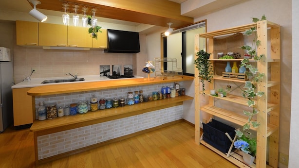 A modern kitchen with a wooden countertop, a brick backsplash, and a built-in shelf with jars. - Z&Z Inn Honjo- Azumabashi (Tokyo)