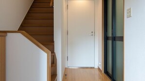 A hallway with a wooden staircase, a door with a frosted glass panel, and a light fixture on the ceiling. - Z&Z Inn Honjo- Azumabashi (Tokyo)