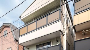 A multi-story residential building with a garage, a bicycle, and a scooter parked outside. - Z&Z Inn Honjo- Azumabashi (Tokyo)