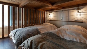 Una habitación con dos camas, vigas de madera e iluminación instalada en la pared.