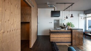 Una cocina moderna con armarios de madera, una isla central, iluminación colgante y un amplio ventanal que proporciona luz natural.