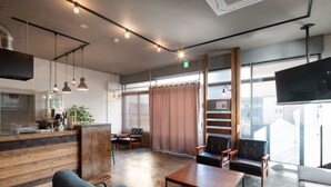 Un interior moderno con un mostrador de recepción de madera, zona de estar y grandes ventanales.
