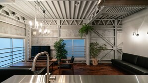 A modern kitchen with a stainless steel sink, wooden flooring, and a large window with a view. - Rakuna Inn Yu Kinshicho (Tokyo)