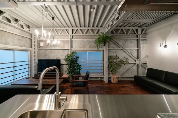 A modern kitchen with a stainless steel sink, wooden flooring, and a large window with a view.