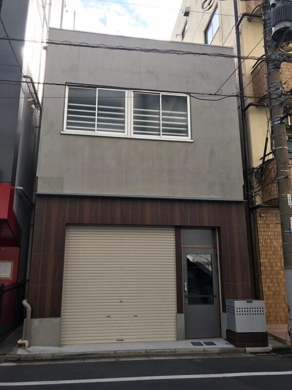 A two-story building with a large garage door and a small entrance door.