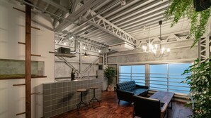 A modern kitchen with a large window, a wooden floor, and a black sofa. - Rakuna Inn Yu Kinshicho (Tokyo)