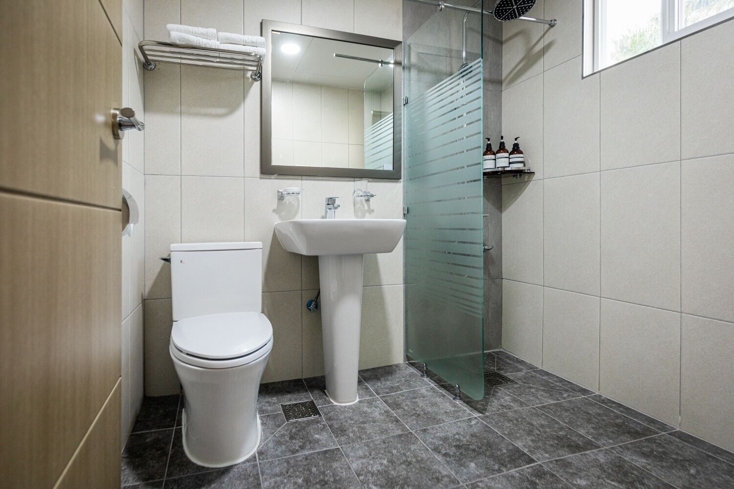 A modern bathroom with a toilet, sink, and glass shower enclosure.