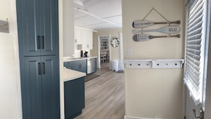 A modern kitchen with blue cabinets, a central island, and a dining area visible in the background.