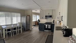 A modern kitchen with white cabinets, a stainless steel refrigerator, a microwave, and a coffee maker.