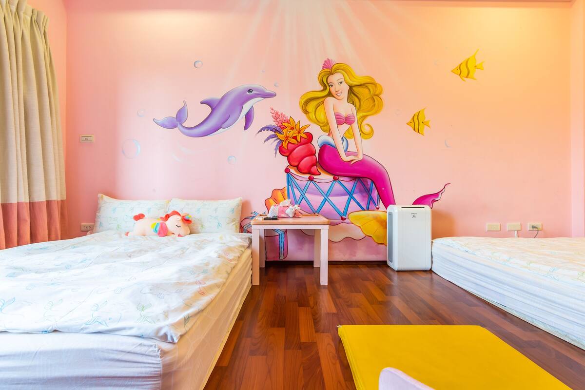 Un dormitorio con cama, una mesita, una silla y un mural en la pared.