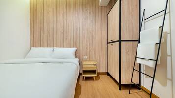A bedroom with a bed, a wooden wardrobe, a small wooden nightstand, and a black metal ladder.