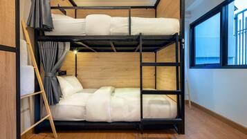 A bunk bed room with wooden walls, a window, and a curtain.