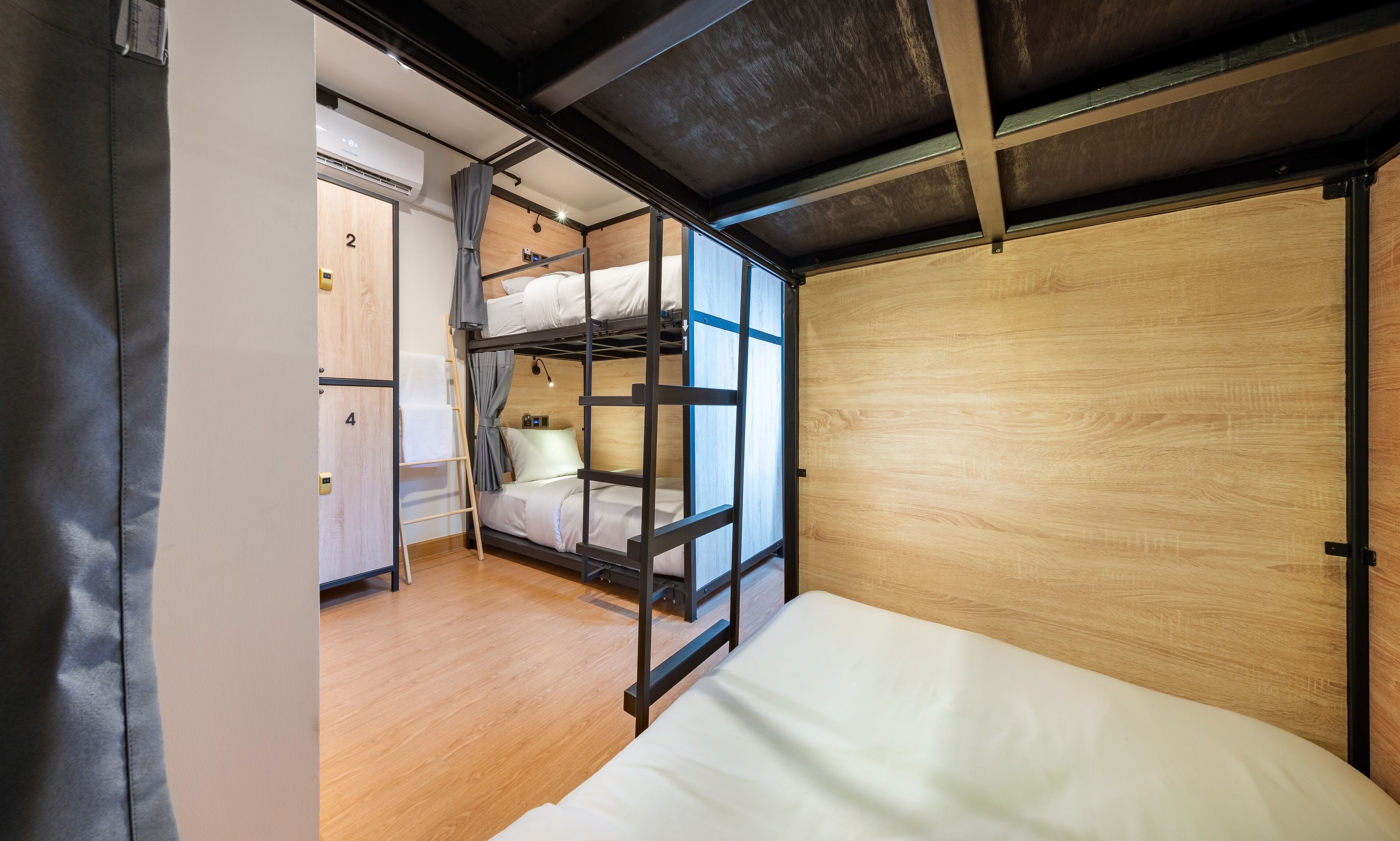 A bunk bed room with a wooden floor, a ceiling with exposed beams, and a door labeled '2'.