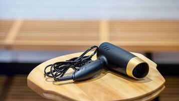 A portable hair dryer and its charging cable on a wooden surface.