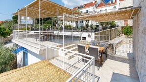 Una terraza en la azotea con mobiliario exterior, un espacio cubierto y vistas de edificios circundantes.
