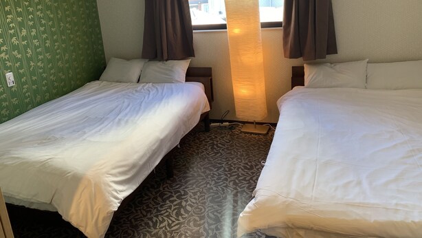 A hotel room with two single beds, a large window with curtains, a lamp, and a patterned carpet. - GH One More Heart Kyoto Station South 5 (Kyoto)