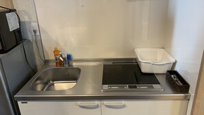 A compact kitchenette with a stainless steel sink, a built-in stovetop, and a small refrigerator. - GH One More Heart Kyoto Station South 5 (Kyoto)