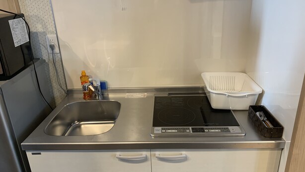 A compact kitchenette with a stainless steel sink, a built-in stovetop, and a small refrigerator. - GH One More Heart Kyoto Station South 6 (Kyoto)