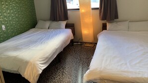 Ein Hotelzimmer mit zwei Einzelbetten, einem großen Fenster mit Vorhängen, einer Lampe und einem gemusterten Teppich.
